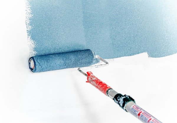 Paint roller applying blue paint for internal and external painting services.